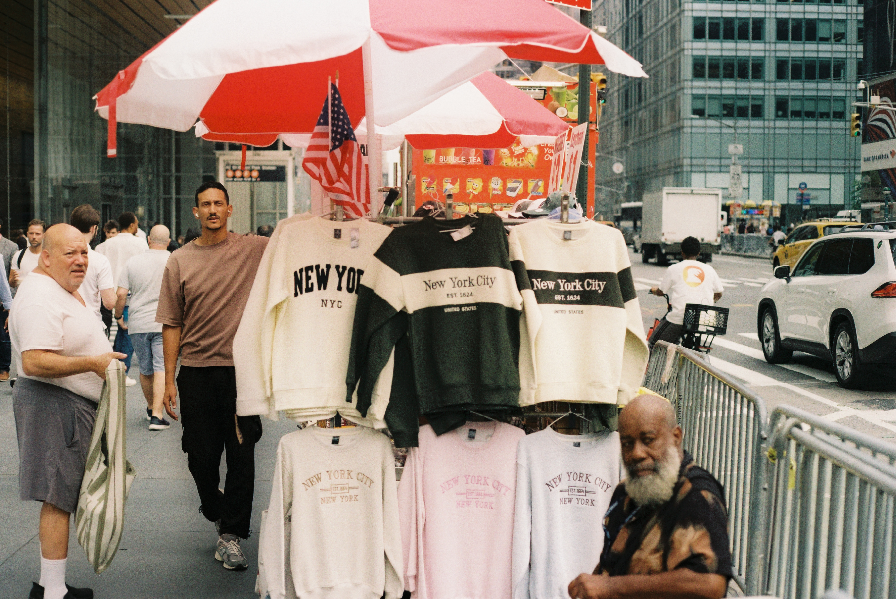Street vendor selling New York City sweatshirts on a busy Manhattan sidewalk