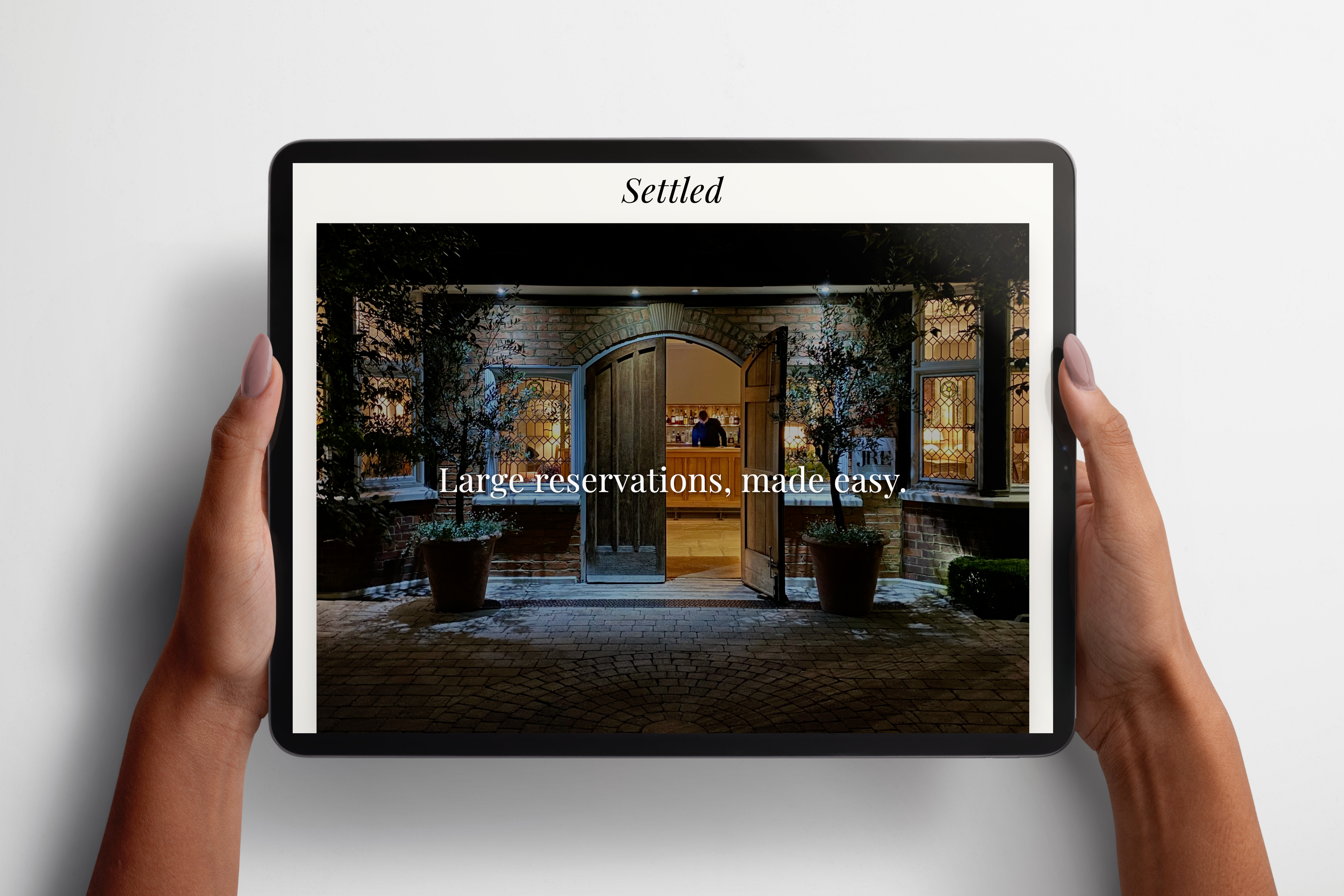 Hands holding a tablet displaying the Settled website